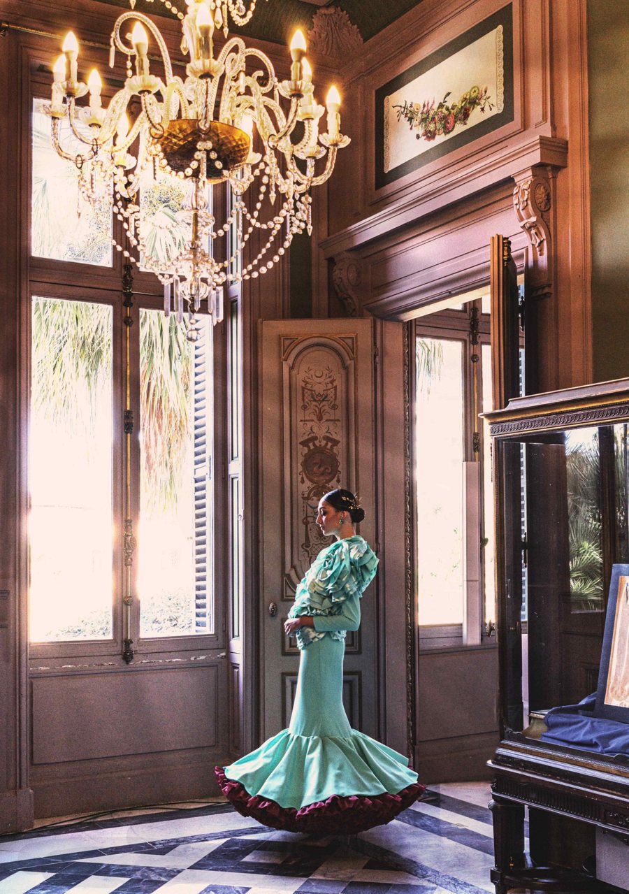 Traje de flamenca turquesa bajo la lámpara de un salón del Palacio